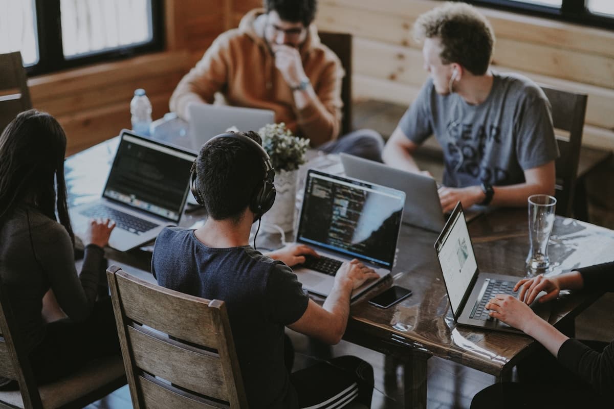 Remote team collaborating on video call with laptops and notebooks
